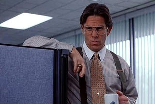 Gary Cole as Bill Lumberg, the evil, dolt of a supervisor in Office Space. He is holding a coffee mug, dressed like a chud in business casual, and leering at the camera with his glasses.