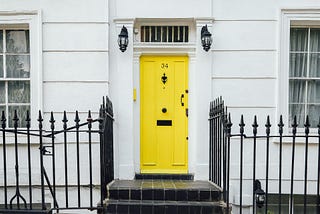 Yellow door to an all white apartment building