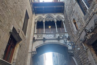 An ornate Gothic pedestrian bridge between two buildings in Barcelona.