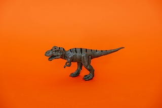 Scrum Masters: You don’t have to have the same fate as the dinosaurs (T-Rex toy on orange background) | Photo by Cup of Couple on Pexels