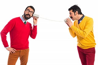 A photo of two men talking to each other using tin cans and string.