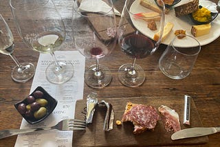 A picture of wine glasses, cheese and cured meats