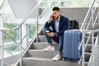 disgruntled traveler sitting on the stairs and talking on his phone