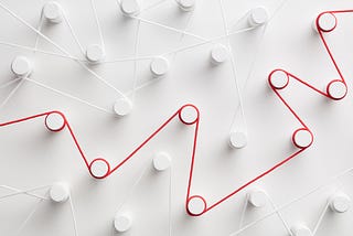 Close-up image of contrasting red and white strings strung between pegs over a white background.