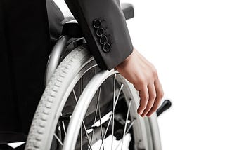 Image shows arm in a suit jacket pushing their wjeel on their manual wheelchair.