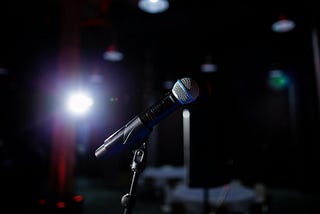 A microphone set up on stage with a spotlight.