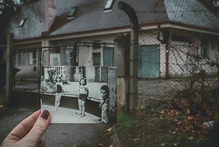 An old photo is held up in front of the building where it was taken a long time ago.