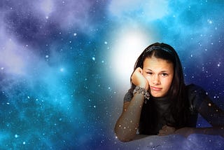 Girl sitting in the foreground in a posture to indicate “thinking” with a colorful galaxy in the background