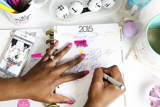 Mãos de uma mulher negra escrevendo em uma agenda em 2015.