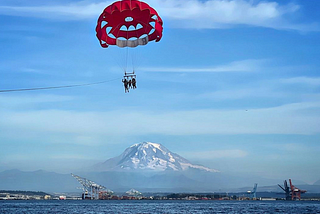 A red parasail in the Puget Sound in Washington with Mount Rainier in the background. Photo by Rene Cizio