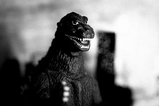 Vintage claymation Godzilla attacking a city