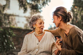 A stock photograph of an old lady and her daughter happily chatting.