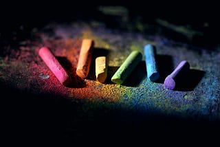 A rainbow of coloured chalk against a black background