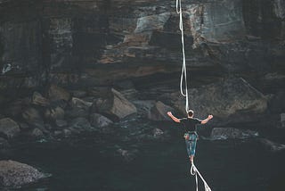 A man on a balance rope walking across a gorge