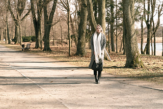 A woman in winter attire strolls through a serene tree-lined park on a sunny day. How to drastically increase your cardiovascular fitness when you can’t go to the gym or go out for a run