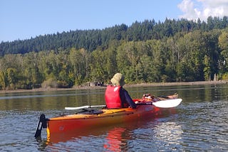 Person kayaking on lake with mountains behind