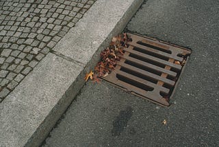 from the top, angled, looking at a drain at the side of a street