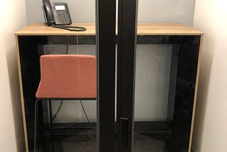 A phone booth room in an office that has a door design that leads people to get trapped into the room.