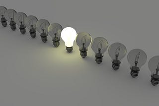 A row of lightbulbs with one lightbulb lit up