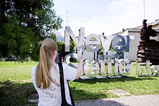 Sophie stood taking a photo of the OnePlus Nord 4 with the Never Settle sign in the background.