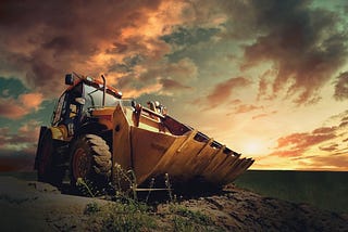 A yellow wheel loader with a golden sky in the background.