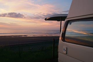 A van with back hatch open facing the ocean