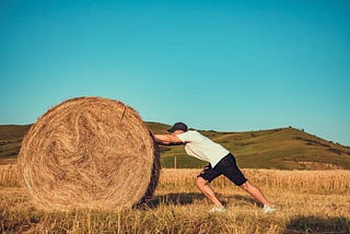 Man pushing hay bale, get rid of wrong mindset and become an achiever