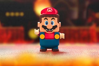 A super mario lego in red, yellow and blue stands on a play ground