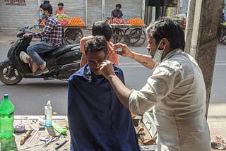 Barber cutting hair in middle of the road in Old Delhi