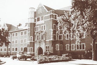 black and white photo of the exterior of Carroll Hall with old fashioned truck parked out front