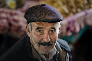 Adorable old man in a flat-cap hat, with beautiful eyes that stare into your soul.