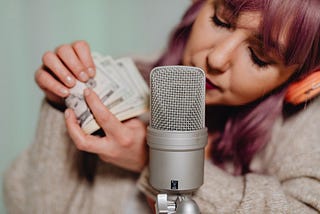 A person behind a microphone holding a a hand full of money.