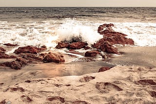 A shot of some footprints in the sand, and the waves