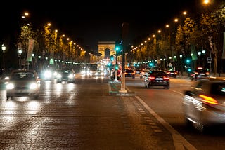 The Champs-Élysées at night, with fast-moving traffic going both ways.