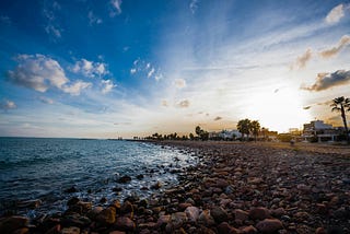 Pebbles on the edge of the ocean with the sunsetting in the background