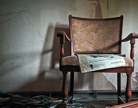 A newspaper left on an easy chair in a now-abandoned house.