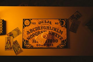 A classic Ouija board, with three Tarot cards on the side
