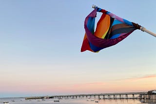 LGBTQI+ flag flying over Provincetown beach at sunset