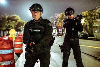 Two actors on a television set in SWAT gear.