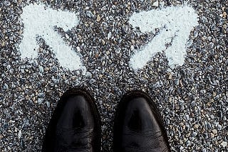 Two arrows pointing in different directions in front of a pair of shoes.