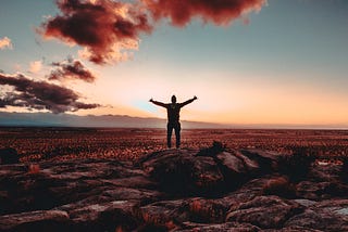 Person standing outside somewhere beautiful with their arms outstretched.