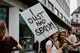 Photo of a small group of women, one holding up a placard with the words “I just had sexism”.