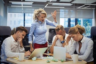 Angry woman boss berating her employees in a meeting