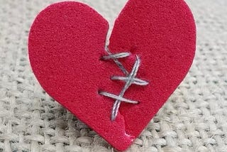 Felt heart with thread mending a tear, as in “repairing a broken heart.”