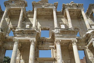 photo of Celsus Library at Ephesus (now part of Selcuk, Turkey), view from ground looking up at the columns and ceiling of ruins, sunny day clear skies