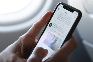 A person browses their twitter feed while sitting on an airplane.