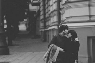 A black and white picture of a boy kissing a girl on her forehead.