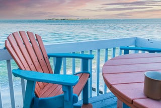 A coffee cup sitting on a table on a waterfront porch