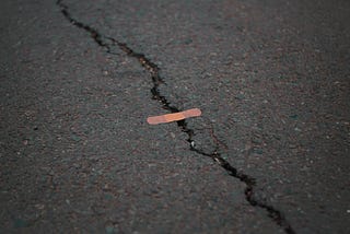 A crack in the road patched with a band-aid.