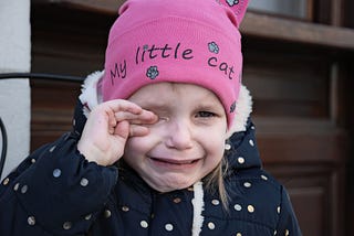 Crying girl wearing a pink hat